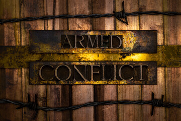 Armed Conflict text formed with real authentic typeset letters on vintage textured silver grunge copper and gold background with barb wire