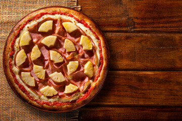 Turkey breast, pineapples and cream cheese Pizza. Top view on wood background, close up. Traditional Brazilian Pizza with smoke.