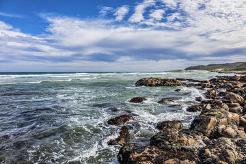 Fototapeta na wymiar Picturesque view of the rocky shoreline of Atlantic Ocean and Platboom Beach. Platboom Bay is a beautiful beach along coastline nestled in Cape of Good Hope Nature reserve, Cape Town, South Africa.
