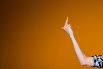 Female hand shows the middle finger on the right of the screen on an orange background. The concept...