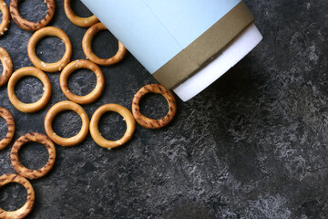 Paper cup, round pretzels and space for text. Abstract dark gray background with lentils and a...