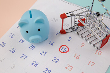 Seasonal sale. Piggy bank with calendar, supermarket trolley on a colorful background.