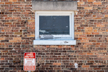 Sign beside a brick building stating that it is private property and warning people to keep out