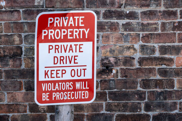 Fototapeta premium Sign beside a brick building stating that it is private property and warning people to keep out