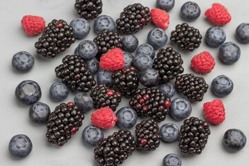 Berries: blackberry, blueberry and raspberry on gray background.