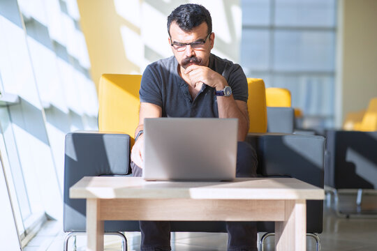 Concentrated toughtful man is looking to laptop screen  in a modern office