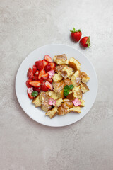 Kaiserschmarren or Kaiserschmarrn, traditional Austrian or German sweet pancake dessert, with berry, strawberry jam or rote grutze and vanilla pudding sauce. Top view. Copy space.