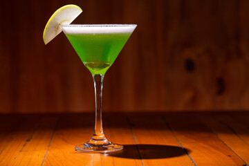 Apple Martini mixed drink with apple slice garnish on wood background