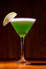 Apple Martini mixed drink with apple slice garnish on wood background