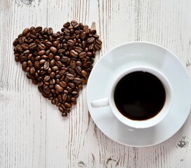 White cup of coffee and coffee beans heart shape. 