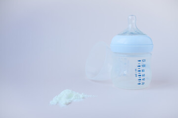 Artificial feeding of babies. Bottle for the mixture, measuring spoon, dry milk adapted mixture. Copy space for text.