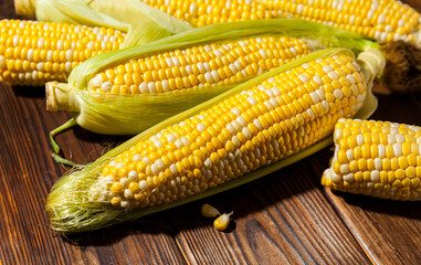 Fresh corn on cobs on rustic wooden table, closeup