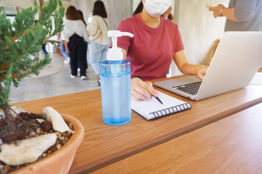 Young Asian woman using hand sanitizer while sitting in cafe