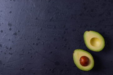 two avocado halves on dark grunge concrete surface