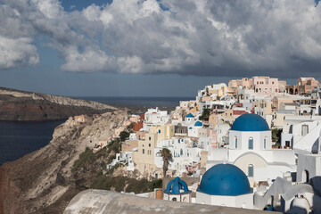 Oia town on Santorini island in Greece. The background is a blue sky with dark clouds. View of...