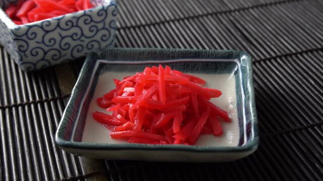 Benishoga, a type of Japanese pickled ginger often used as a side dish next to yakisoba, ramen, and other traditional dishes. 4K rotating shot.