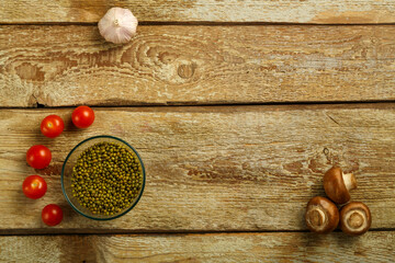 On a wooden table is a cup of mung bean and vegetables. Copy space.