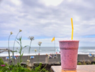 a big vessel with strawberry milkshake is on the right front in the picture on a table