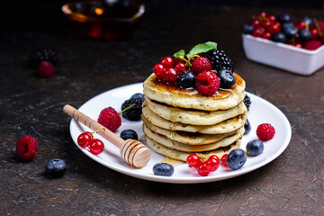 Sweet Homemade Pancakes with berries, honey or maple syrup on black background. Morning breakfast concept