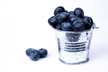 Sweet red currant in little metal decorative bucket on white background.