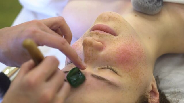 Facial massage with brushes and stone. Close-up face of a young woman. High quality 4k footage