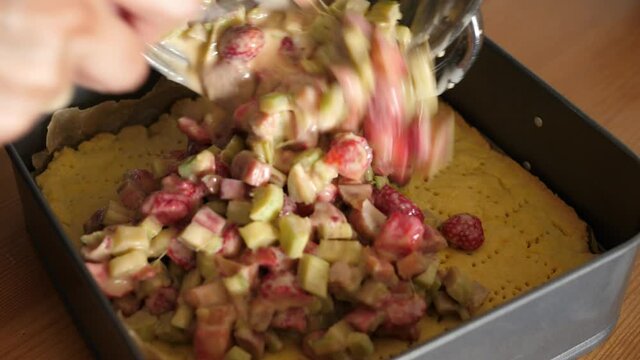 preparing a cake with strawberries and rhubarb filling