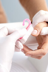 Close up of manicure master hands removing dust from client nails by brush in nail salon