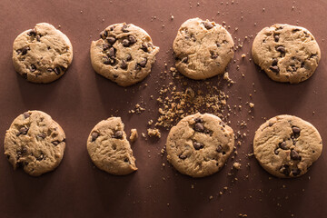 Broken chocolate chip cookies on brown background