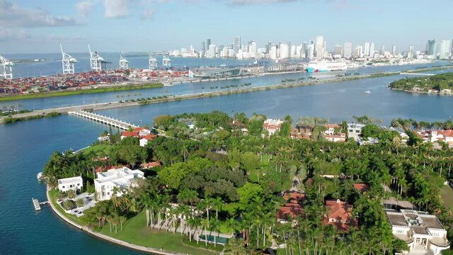 Slow motion top view on Star Island with Miami port and downtown on a background. Clear green water surrounds lavish nature of tropical island. 4K aerial stock video for tourism business. Florida, USA