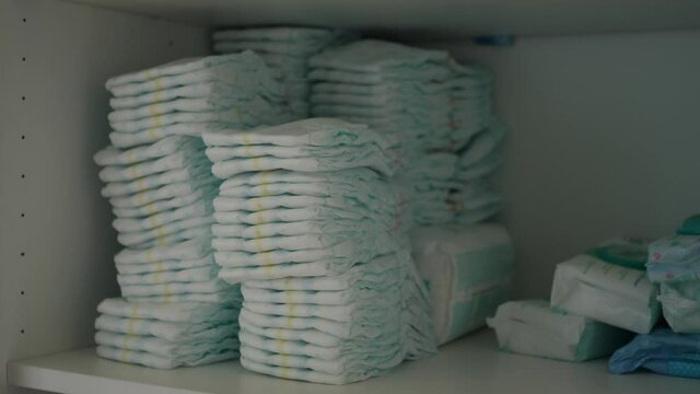 hands take a disposable diaper from the cupboard drawer