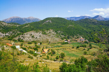 Obraz premium Summer mountain landscape with small village in valley. Sunny day in Dinaric Alps, Montenegro, Sitnica region