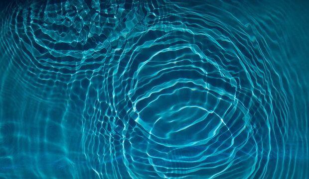 Kreisrunde Verwirbelungen im kristalblauen Wasser von herabfallenden Wassertropfen