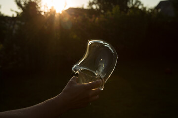 Splash of water in a glass. Flying water. A glass of water in a man's hand in the sunset.
