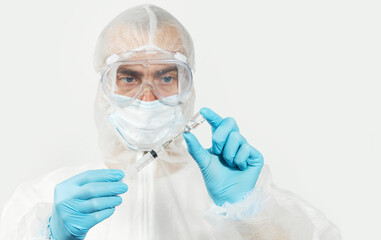 Male doctor  in blue nitrile gloves, glasses and a respirator mask for protection holds a vaccine bottle and syringe for injection. Coronavirus Vaccine concept.