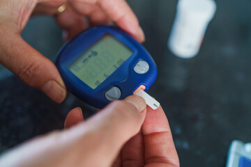 Medicine, Diabetes, Glycemia, Health care and people concept - close up of female using lancelet on finger to checking blood sugar level by Glucose meter