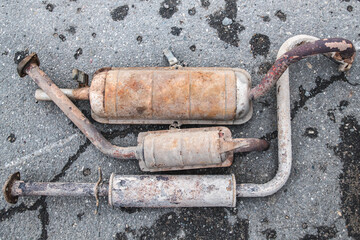 rusty car exhaust system on the pavement