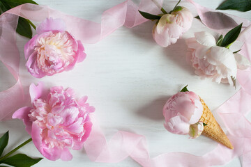 Background with pink peonies, ribbon, waffle cone with a bud and space for congratulation text.