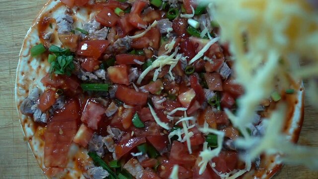 Cooking Pizza. Unbaked Pizza Is Sprinkled With Grated Cheese In Slow Motion. View From Above