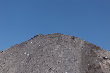 Gray mound of dirt isolated against blue sky