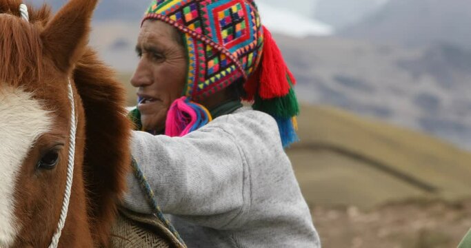 Quechua men packing and loading horse to cross the Andes, Peru.