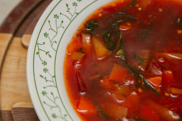 Prato de sopa de beterraba com outros legumes sobre tábua de madeira.