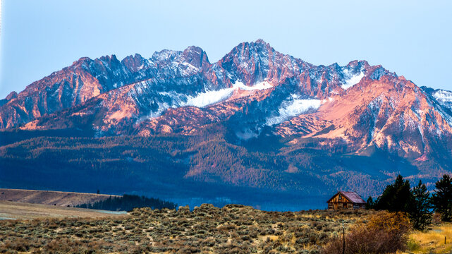 The Sawtooth mountains and a log cabin at sunrise near  Stanley, Idaho.