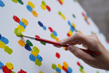 Hand painted colorful abstract minimalist canvas image. A young female hand paints a picture with a brush. Leisure activities at home. © Varga_photography