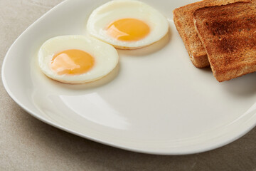 two eggs sunny side up with 2 toasted integral bread on a white plate