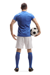 Full length rear shot of a soccer player with a ball under arm