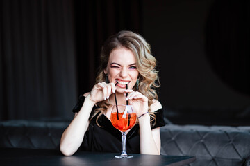 Beautiful blonde, young girl holding an aperol spritz. Aperol cocktail syringe in a glass. Portrait...