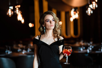 Beautiful blonde, young girl holding an aperol spritz. Cocktail aperol spritz in a glass. Portrait...