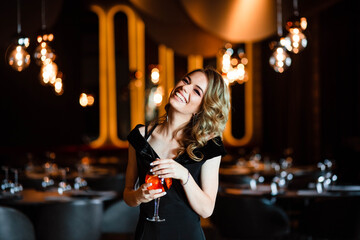 Beautiful blonde, young girl holding an aperol spritz. Cocktail aperol spritz in a glass. Portrait...