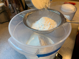 Sifting White Flour into a Bucket to be Used to Bake Bread at Home During Quarantine