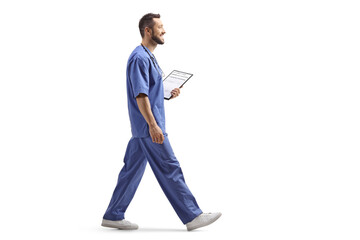 Male health worker in a blue uniform walking and holding a clipboard